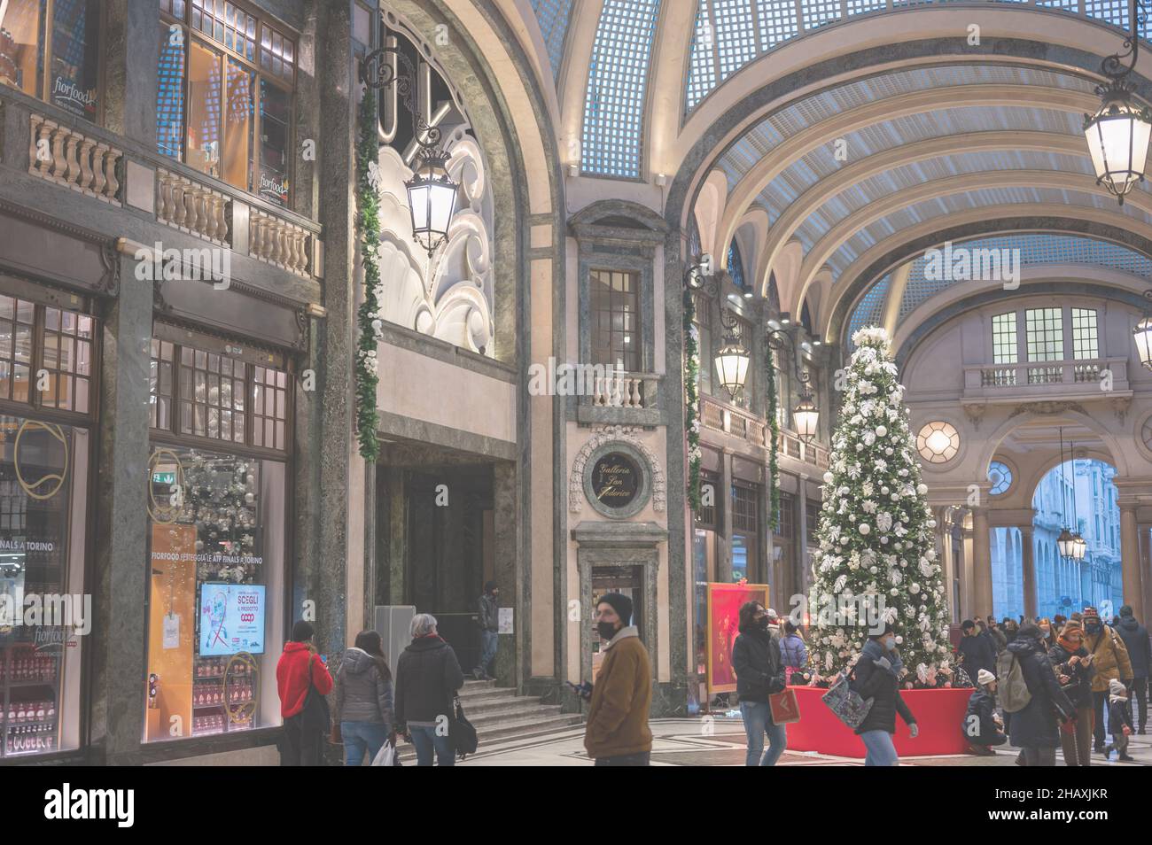 Turin, Piedmont, Italy. December 2021. The Christmas tree has been set up at the San Federico gallery. Passage of people with masks to defend themselv Stock Photo