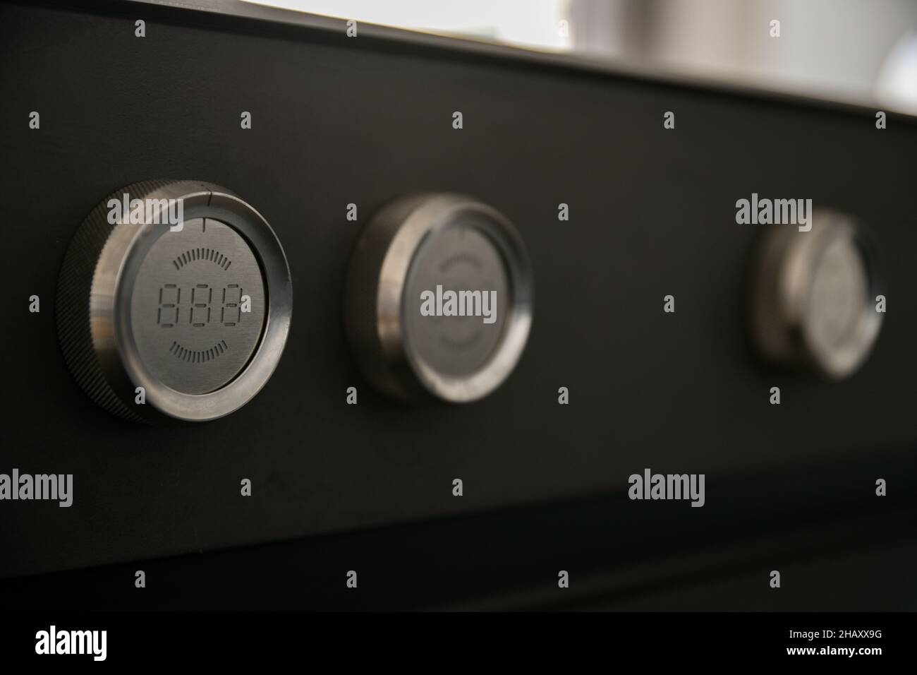 Closeup of light metal round knobs of new black modern oven in kitchen