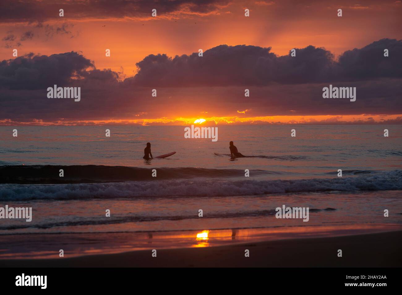 Distant silhouette of two people, surfing at sunset, El Palmar beach, Cadiz, Andalusia, Spain Stock Photo