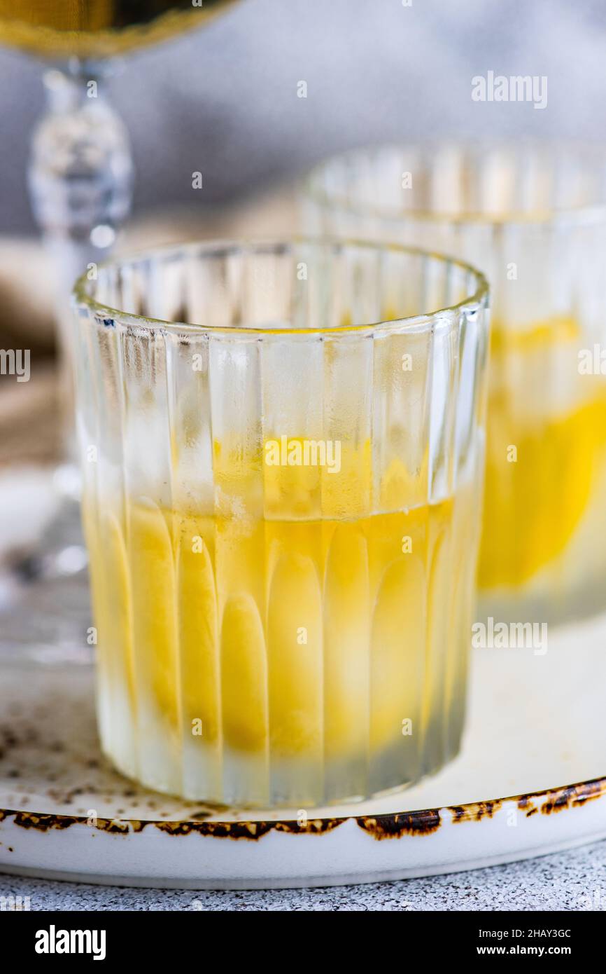 Two glasses of vodka cocktails with lemon and ice cubes on a table Stock Photo