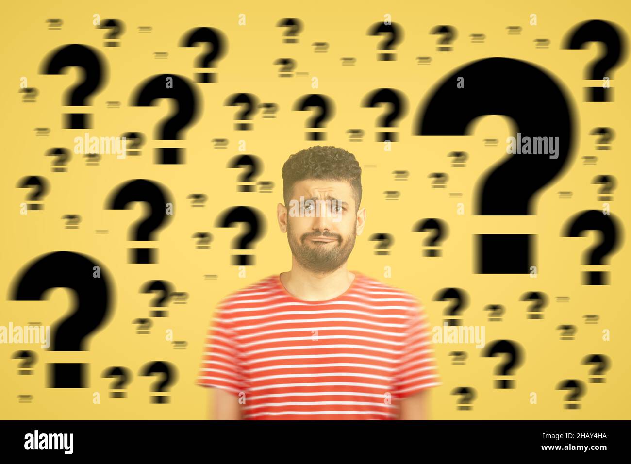 Confused thoughtful man looking with pensive sad face. work pressure, trouble, overthinking concept. indoor shot on yellow background with many question mark. Stock Photo
