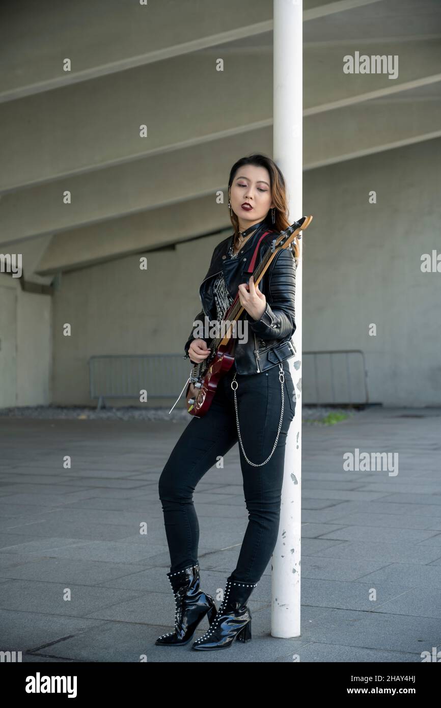 Portrait of an edgy gothic Asian woman playing the guitar Stock Photo