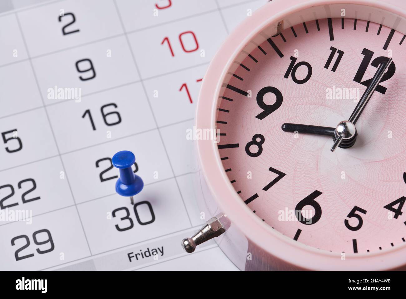 Deadline concept with push pin on monthly calendar and alarm clock