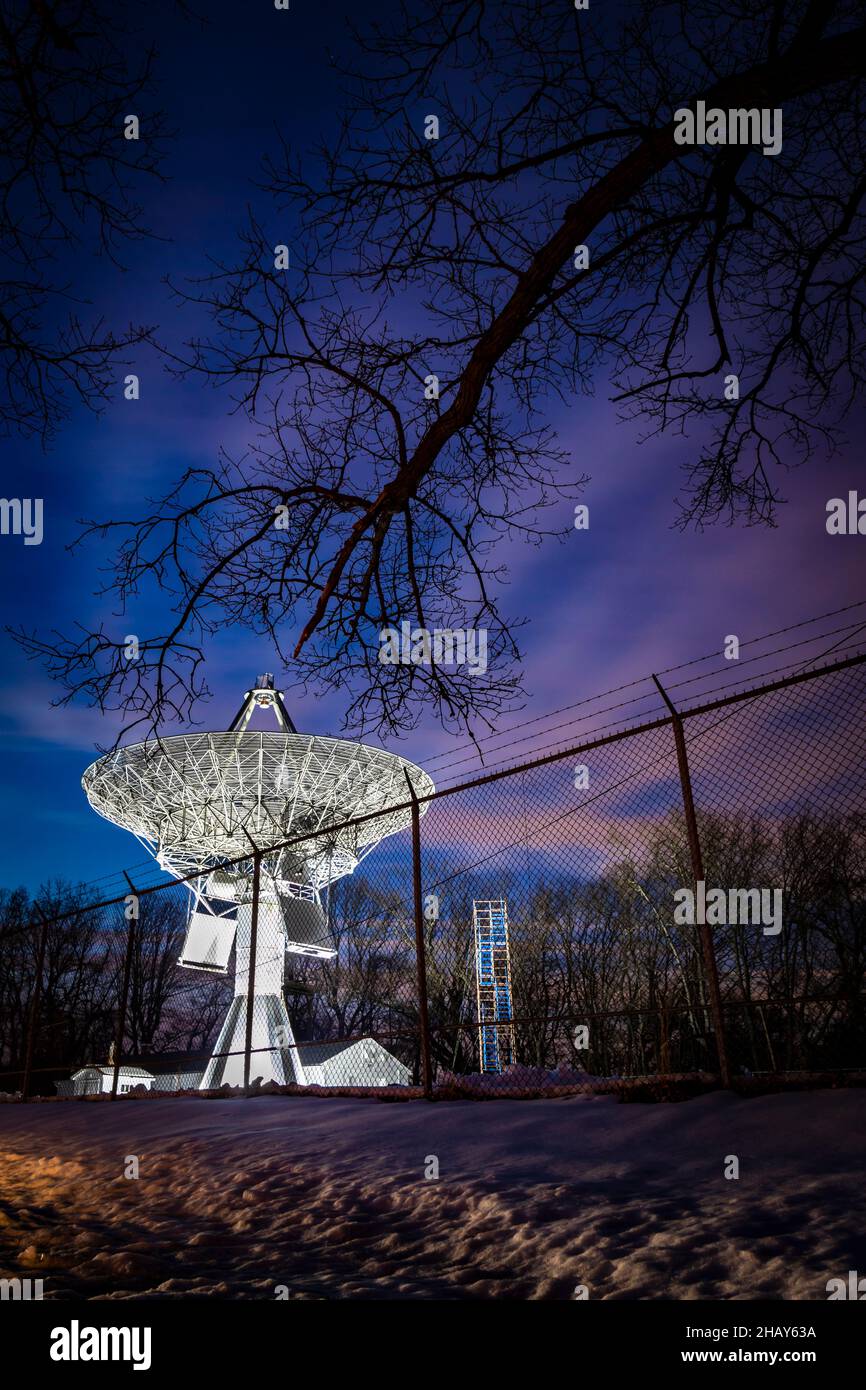 Colorful twilight skies over the Project Diana satellite dish at Camp Evans, fenced in and pointed to outer space Stock Photo