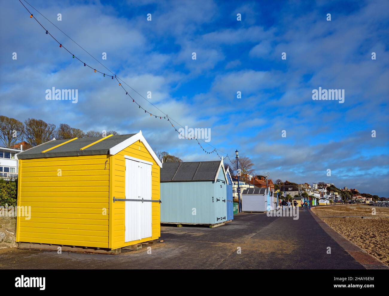 Felixstowe, Suffolk, UK : The promenade in the English resort town of Felixstowe with people walking past a line of bright colorful beach huts. Stock Photo