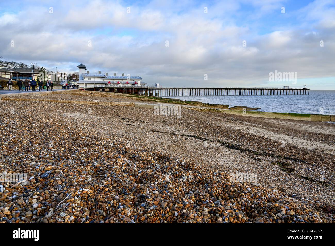 Felixstowe, Suffolk, UK: view of Felixstowe pier from the pebble beach. People walk along the promenade. Stock Photo