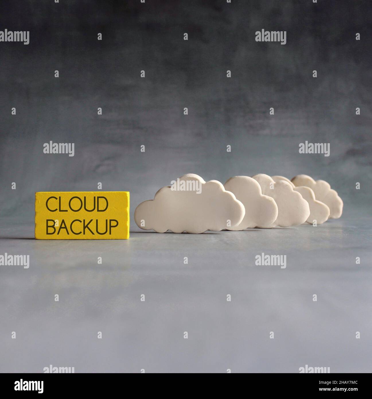 Cloud computing concept. White clouds and wooden cubes with text CLOUD BACKUP Stock Photo
