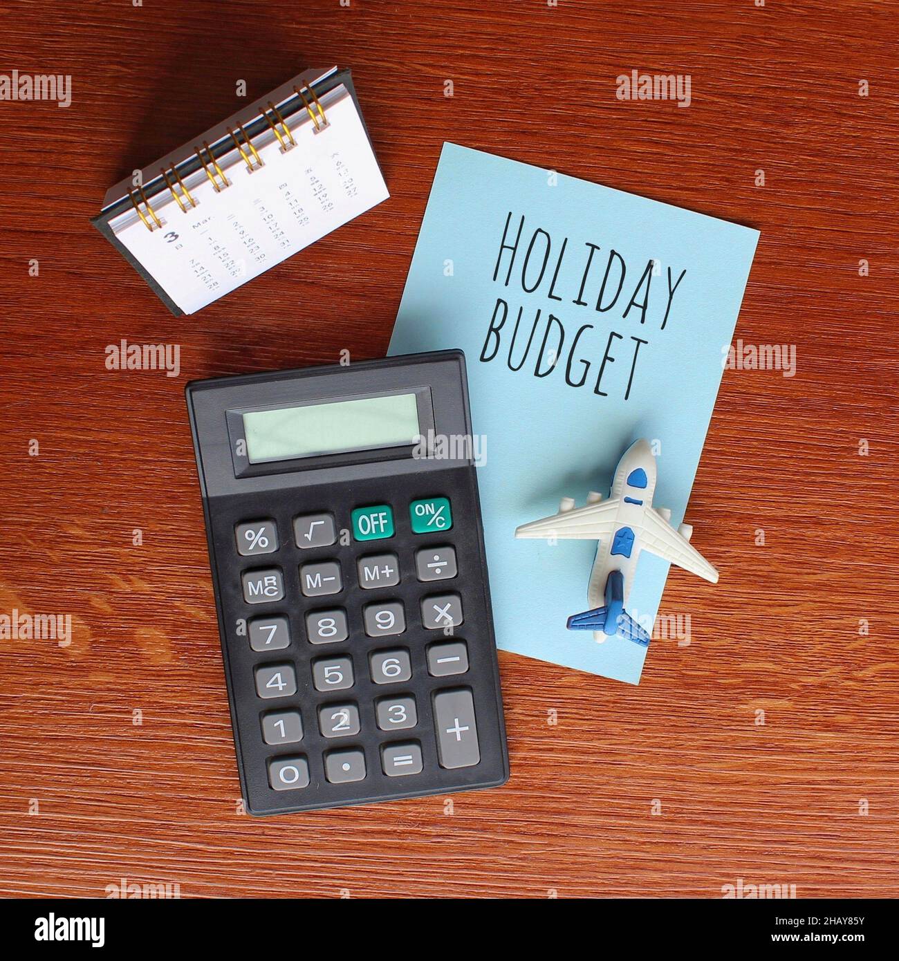 Planning and financial concept. Top view of desk calendar, calculator, toy plane and paper with text HOLIDAY BUDGET Stock Photo