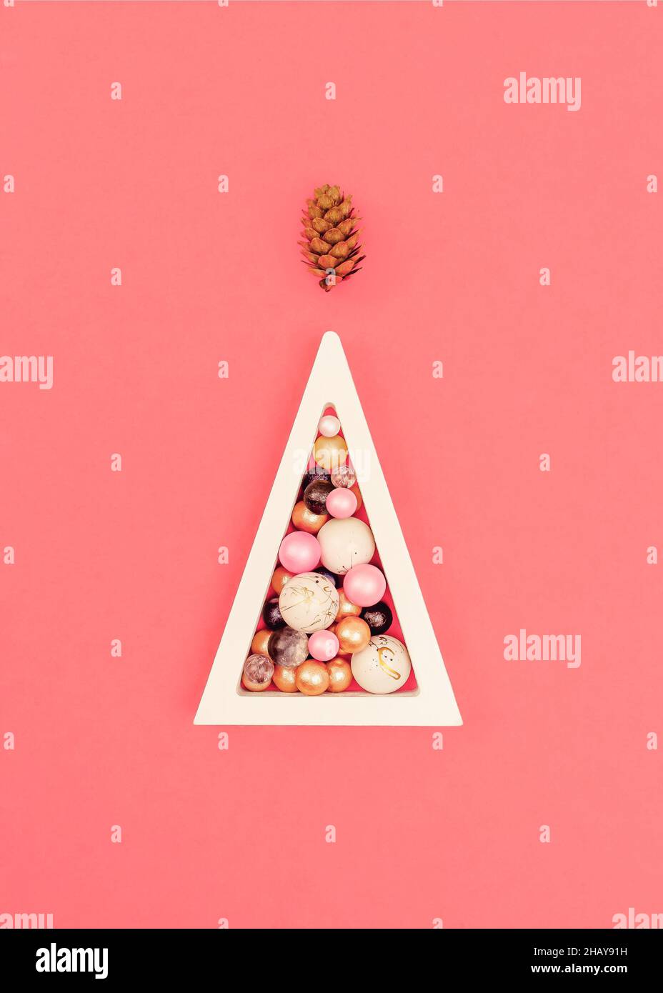 Abstract Christmas tree concept. A wooden white triangle with colorful balls. Marble and pearl balls. A pine cone-like the top of a Christmas tree. Co Stock Photo
