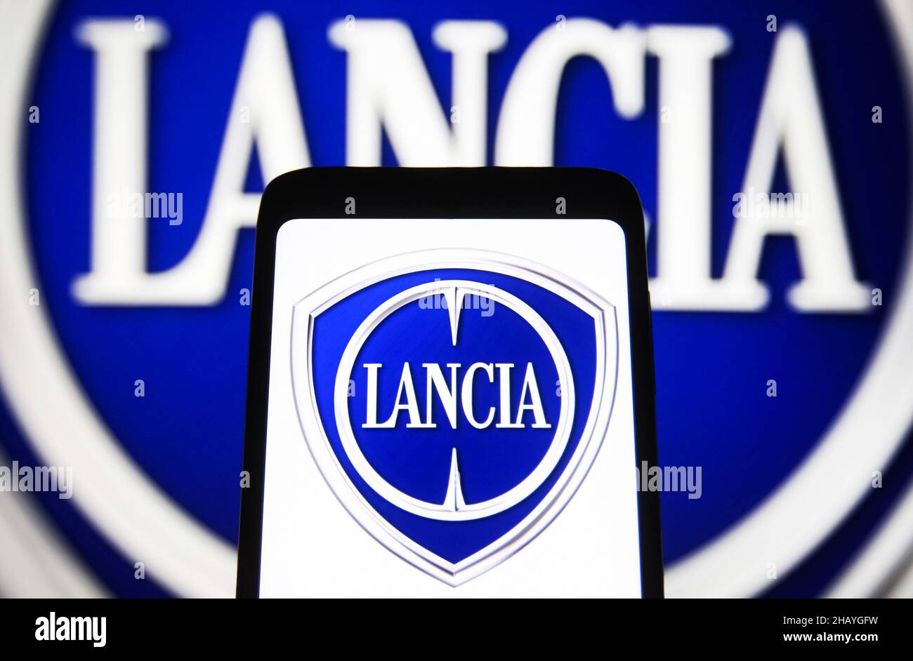 Ukraine. 15th Dec, 2021. In this photo illustration, Lancia logo of an Italian car manufacturer seen displayed on a smartphone and in the background. (Photo by Pavlo Gonchar/SOPA Images/Sipa USA) Credit: Sipa USA/Alamy Live News Stock Photo