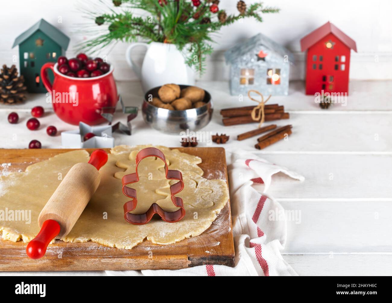 Gingerbread man cookie cutter and rolling pin on cookie dough with Christmas decorations on a table Stock Photo