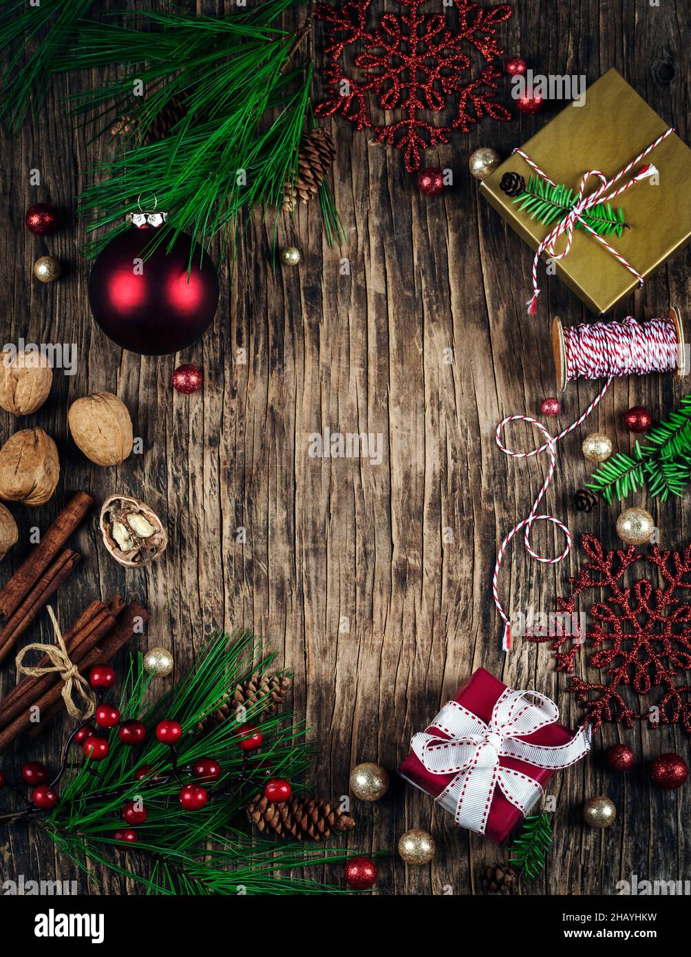 Overhead view of Christmas gifts, baubles, decorations, walnuts and cinnamon sticks on a wooden table Stock Photo