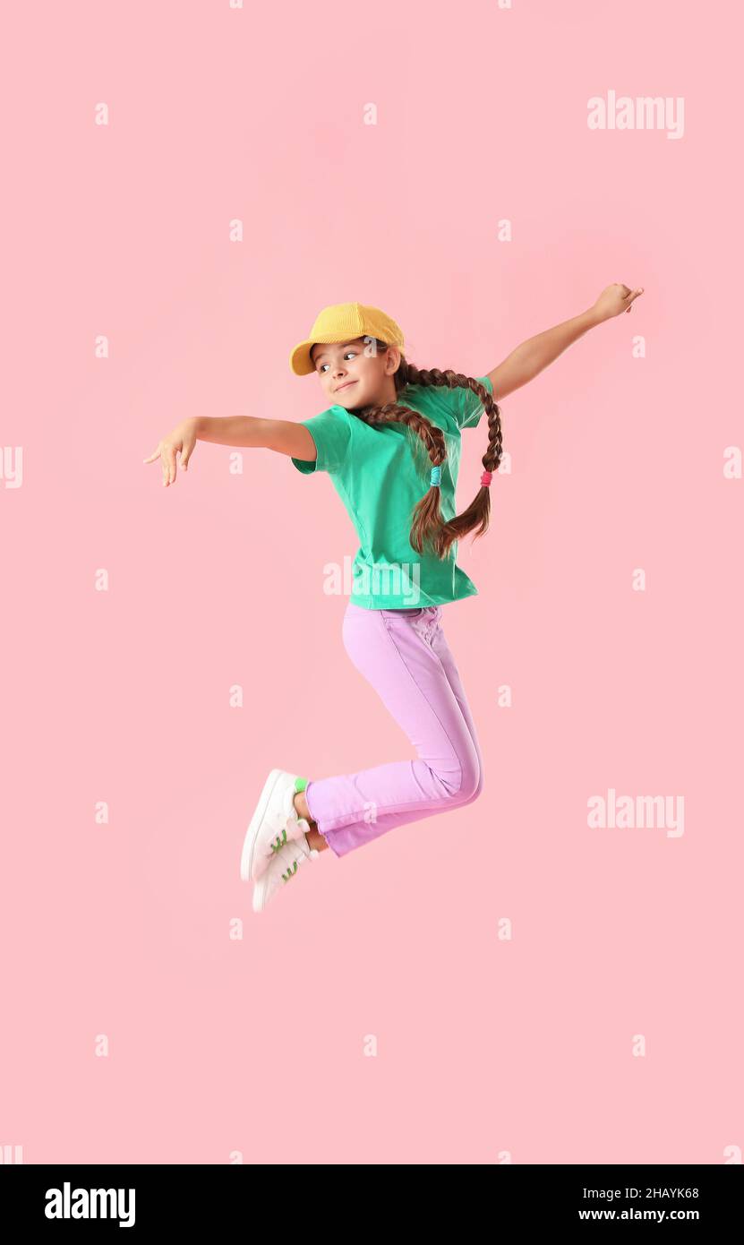 Cute little girl in cap jumping on pink background Stock Photo Alamy