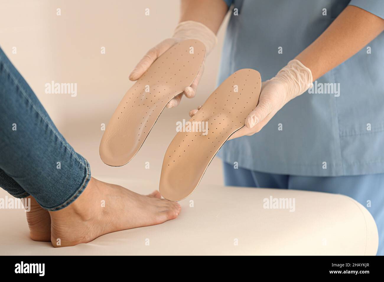 Female orthopedist showing beige insoles to patient in clinic, closeup ...
