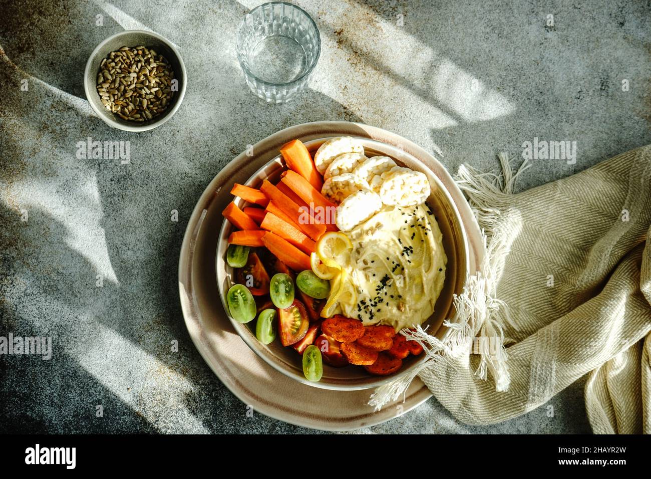 Hummus and vegetables crudites with rice crackers, sunflower seeds and