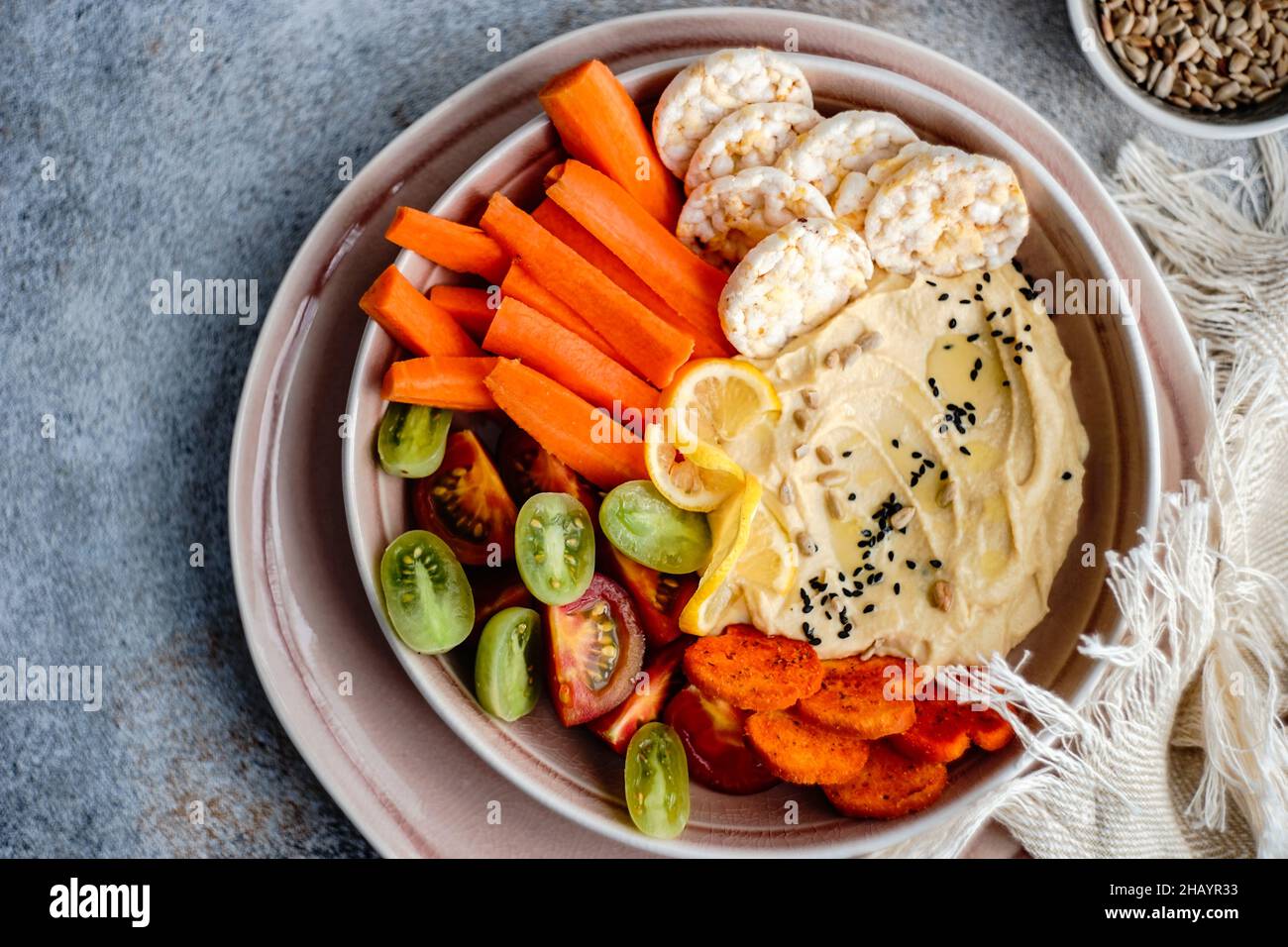 Hummus and vegetables crudites with rice crackers and sunflower seeds