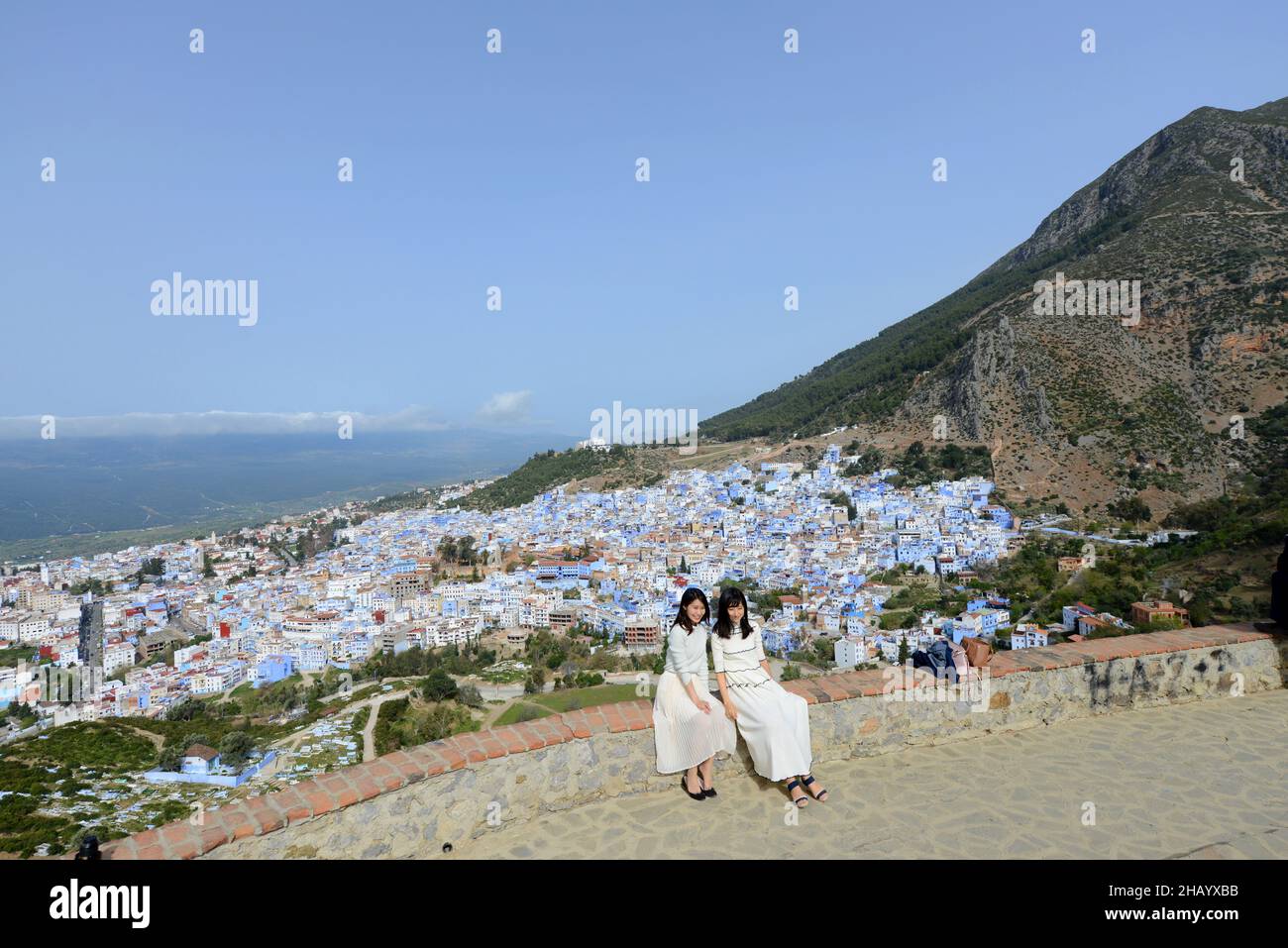 Asian tourist posing for a shot with the view of the Blue City of Chefchouen in the Rif mountains in Morocco. Stock Photo