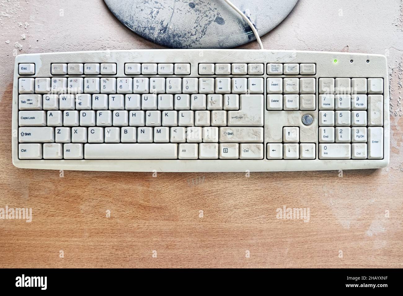 Old keyboard and broken monitor are on wooden table and covered in thick dust in a workshop. Top view Stock Photo