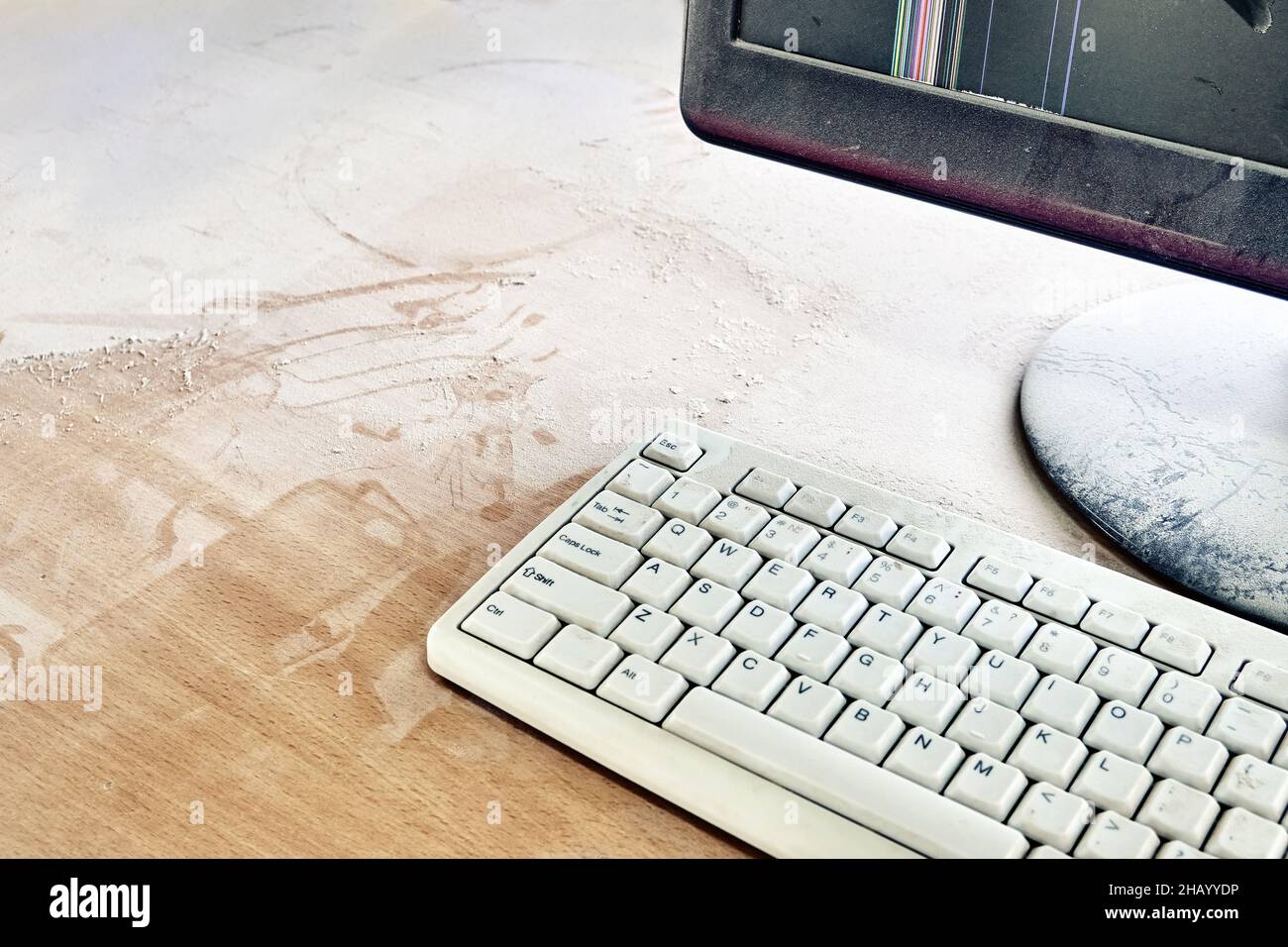 Old keyboard and broken monitor are on wooden table and covered in thick dust in a workshop closeup Stock Photo