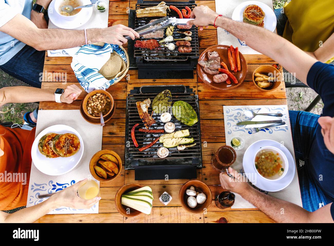 Group of latin friends eating mexican tacos and traditional food, snacks and people's hands over table, top view. Mexican cuisine Latin America Stock Photo