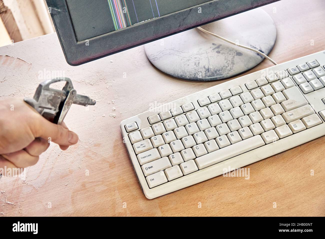 Employee cleans a dusty keyboard and dusty desk with air duster