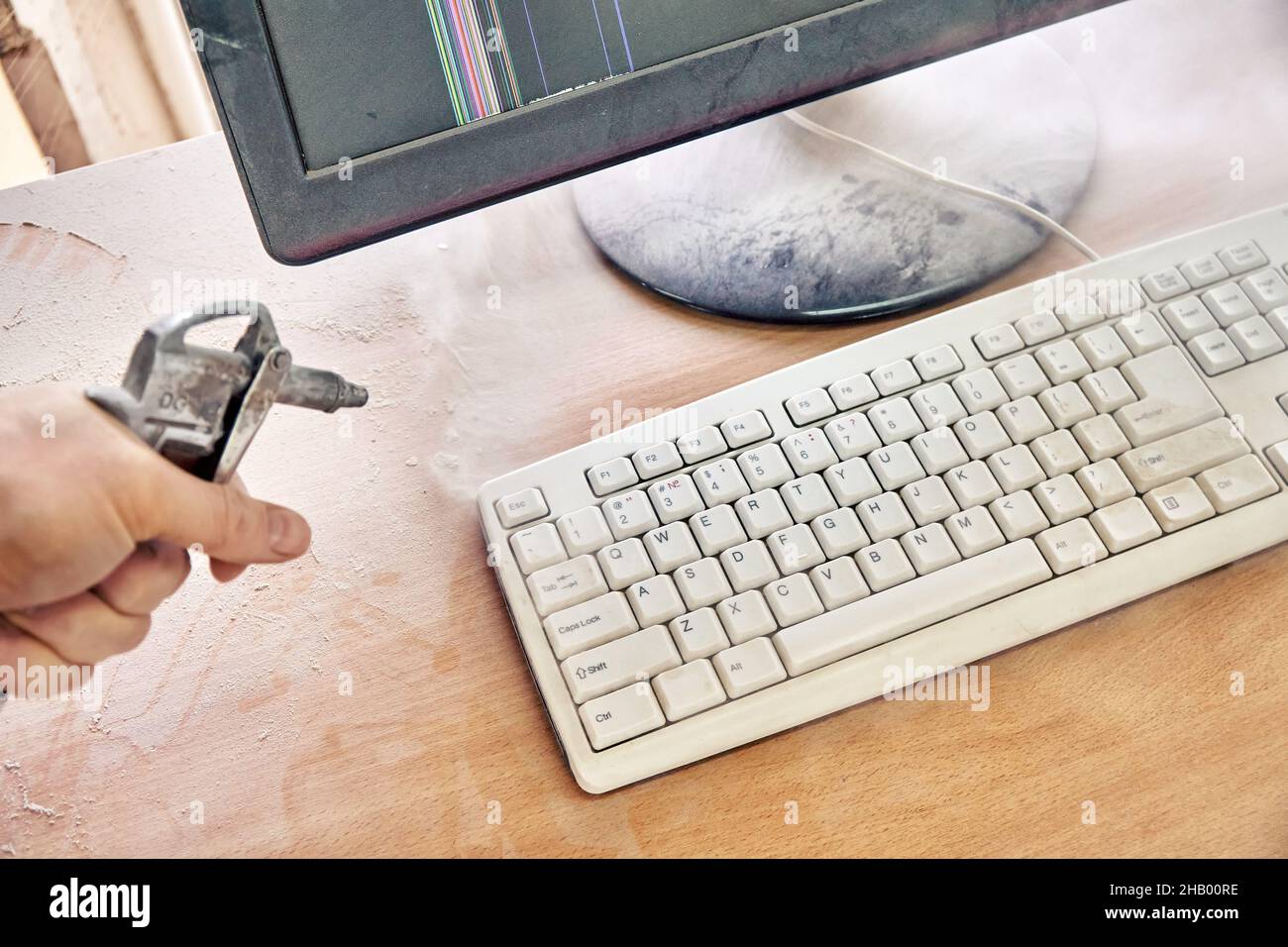 Employee cleans a dusty keyboard and dusty desk with air duster