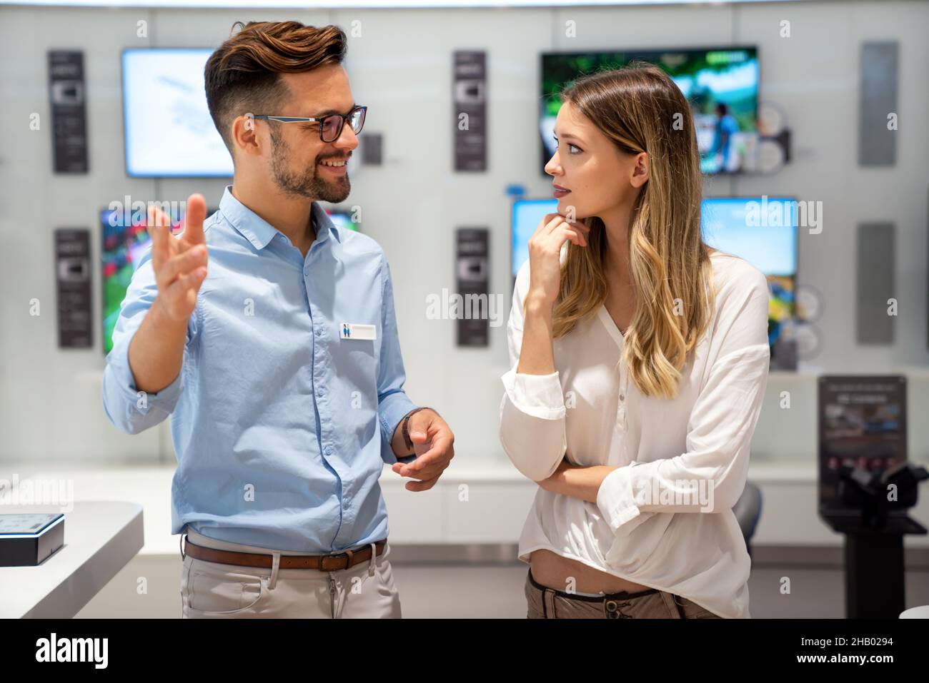 Happy people in consumer electronics retail store looking at new digital device Stock Photo