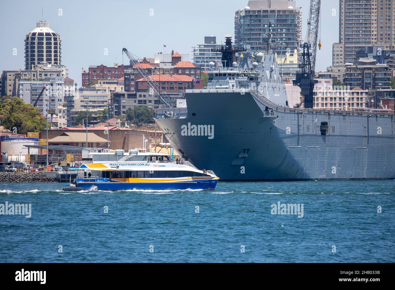 Manly fast ferry passes garden island,australian naval base and HMAS Canberra ship, Sydney, Australia Stock Photo