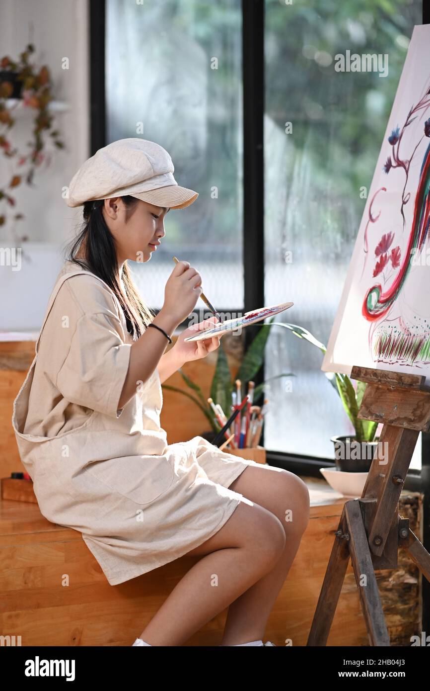 Smiling asian girl painting on canvas in art workshop Stock Photo - Alamy