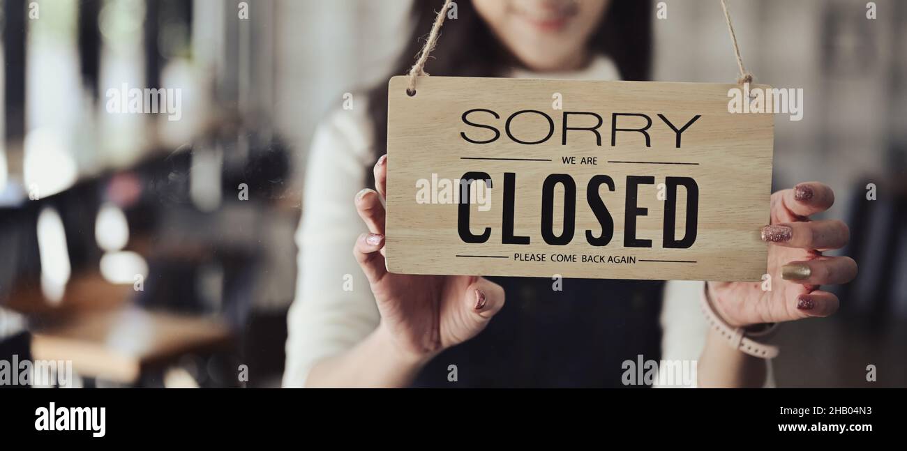 Small business owner turning closed sign board on the entrance door. Stock Photo