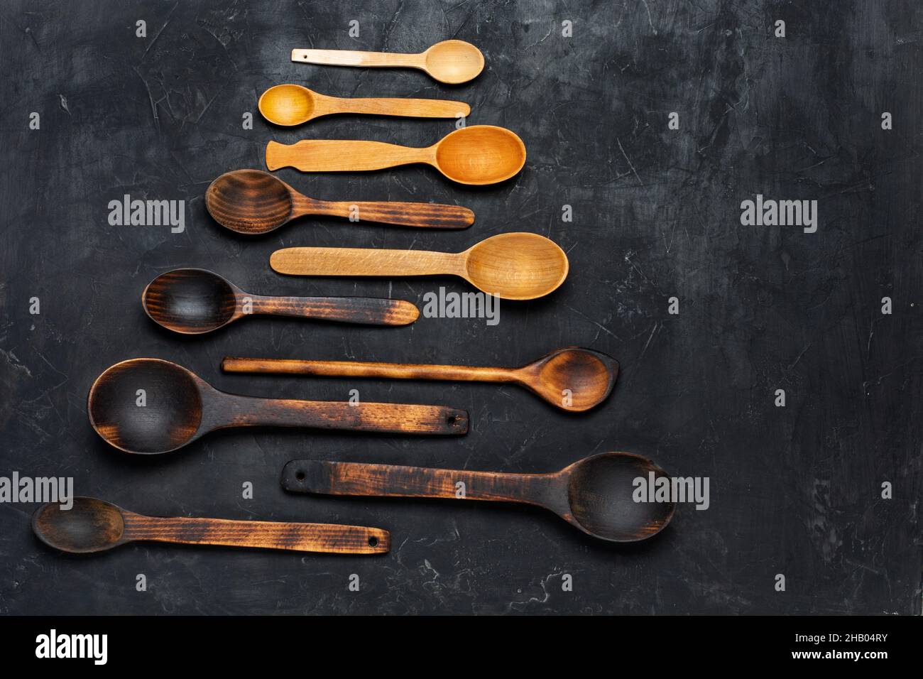 Wooden spoons on dark wooden background. Top view, copy space. Stock Photo