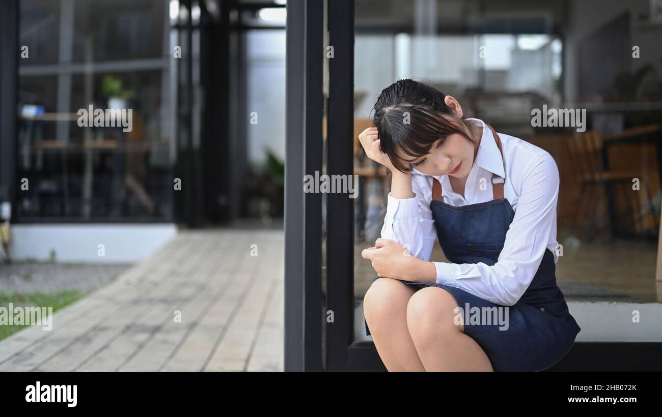 Stressed Asian cafe owner feeling worried about financial problem. Stock Photo