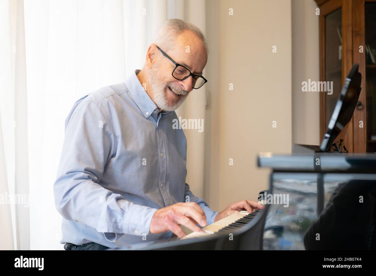 Old man play on piano at home Stock Photo