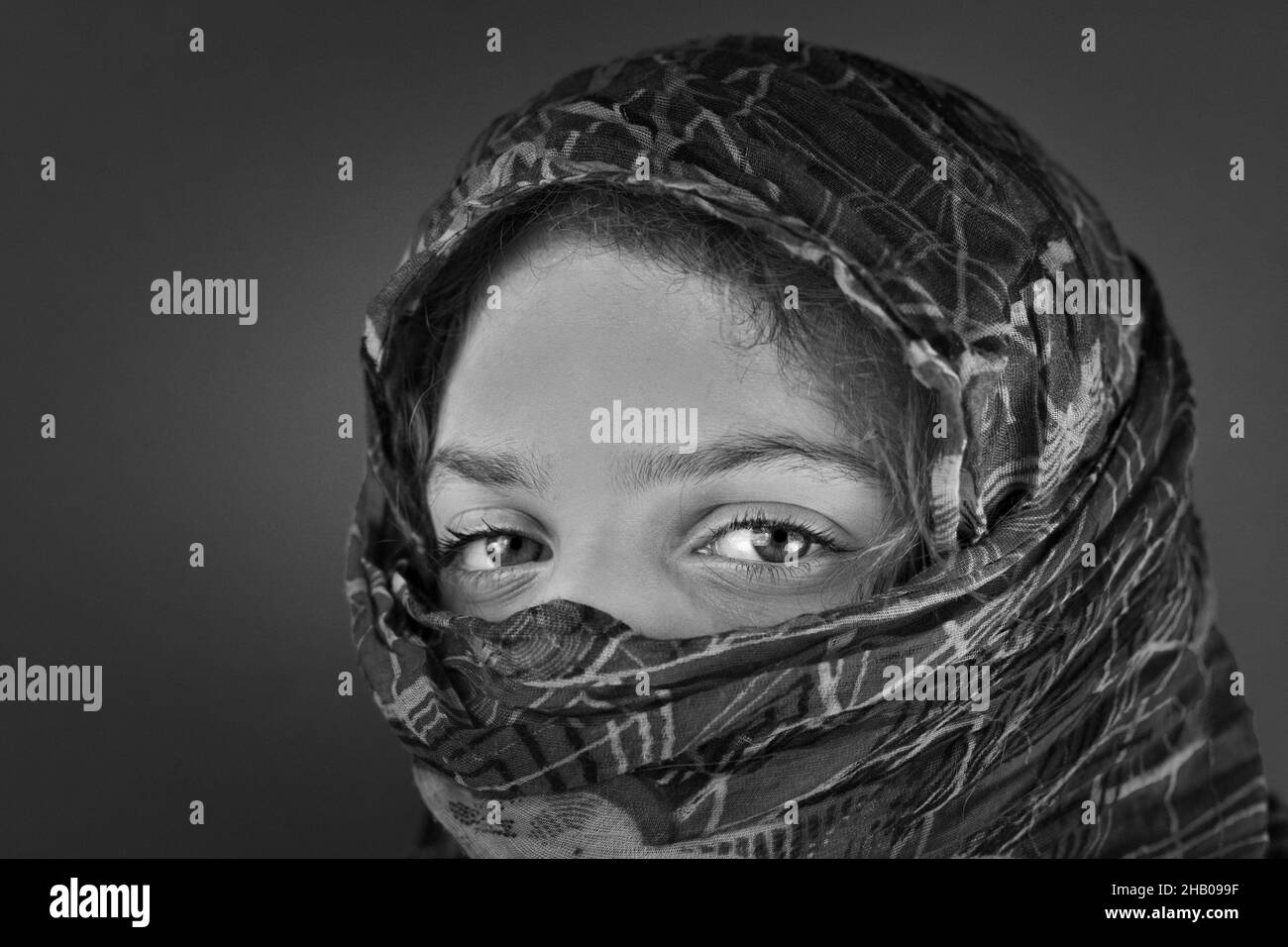 Grayscale shot of a Caucasian female with a headscarf with patterns Stock Photo
