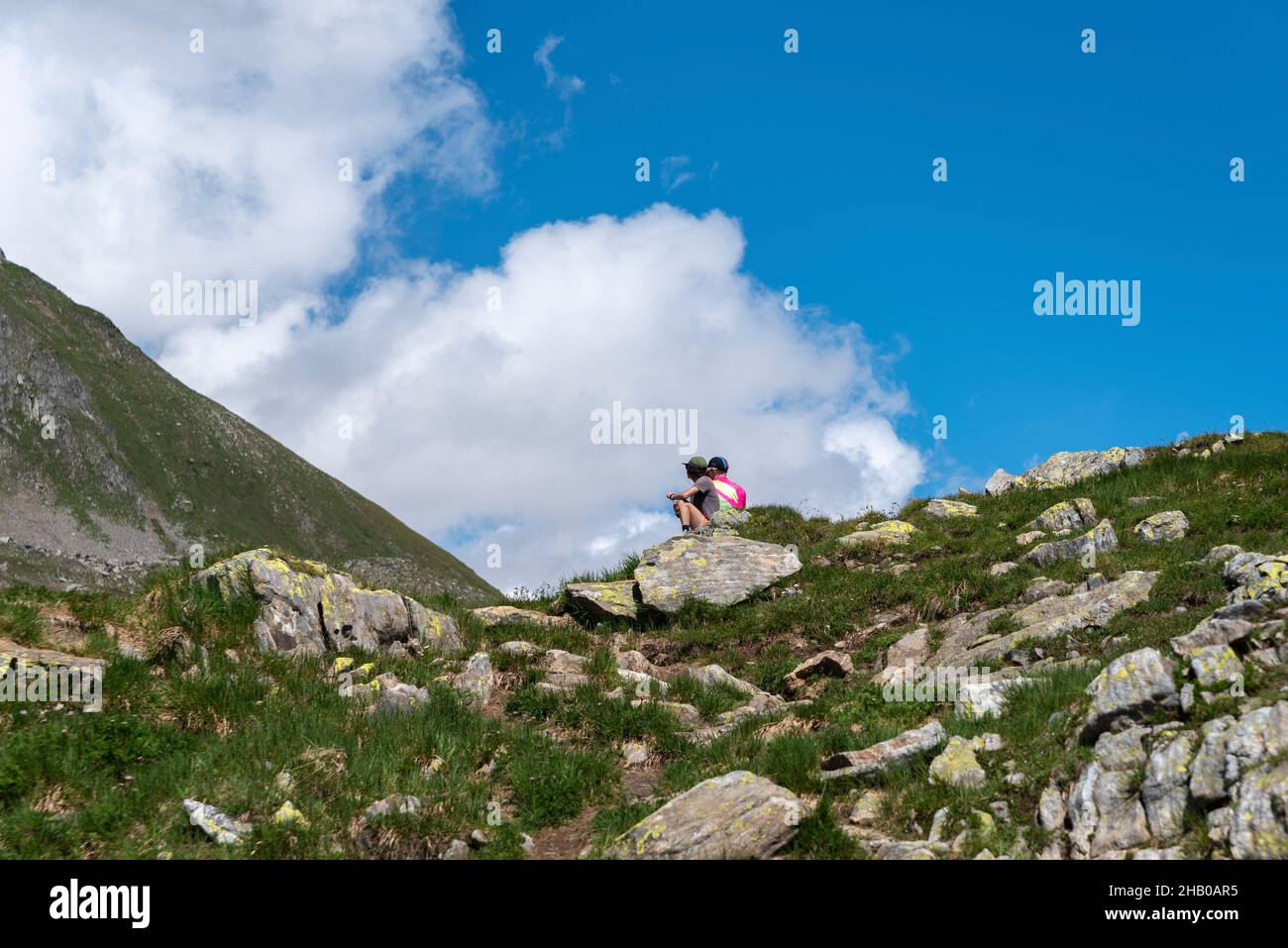 Hikers rest in alpine landscape by the Nufenen Pass, Ulrichen, Valais, Switzerland, Europe Stock Photo