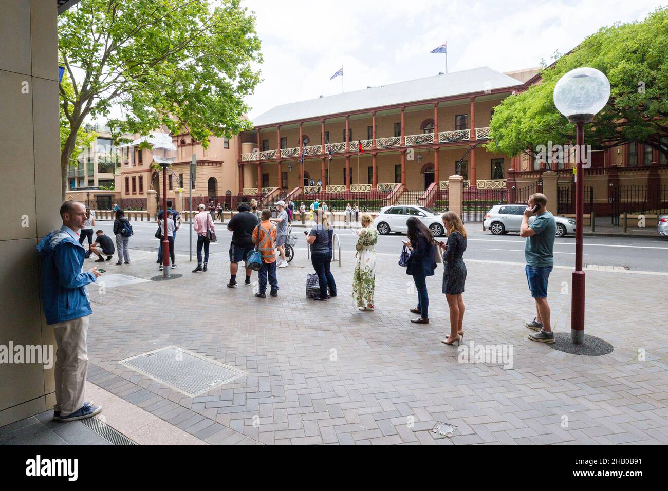 Sydney, Australia. 16 Dec 2021. The 'Declare Your Rights' anti-vaccination protest in Sydney, Australia. The event commenced at Parliament House on Macquarie Street with a march across Sydney Harbour Bridge to descend on Kirribilli House, the Prime Minister's residence in Sydney. Pictured: Sydney residents in a long queue at a COVID-19 testing facility on Macquarie Street opposite Parliament House while a COVID-19 anti-vaccination protest is taking place. Credit: Robert Wallace / Wallace Media Network / Alamy Live News Stock Photo