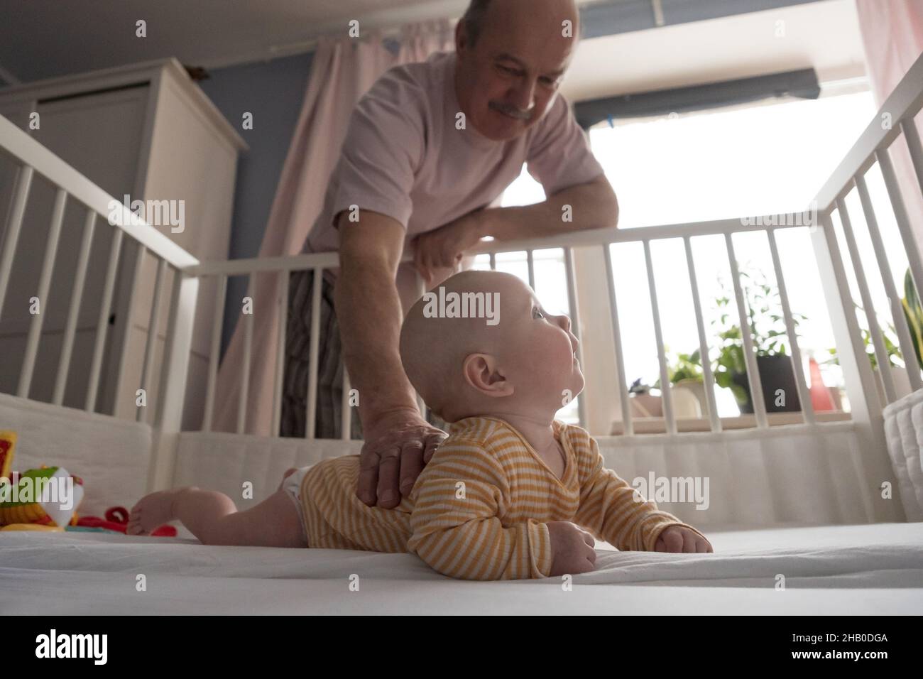 Cheerful senior grandfather playing with grandson at the bedroom Stock Photo