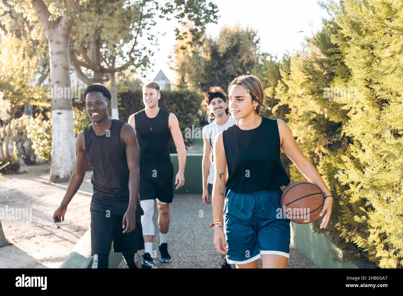 Four friends walking to a path with a basketball ball Stock Photo