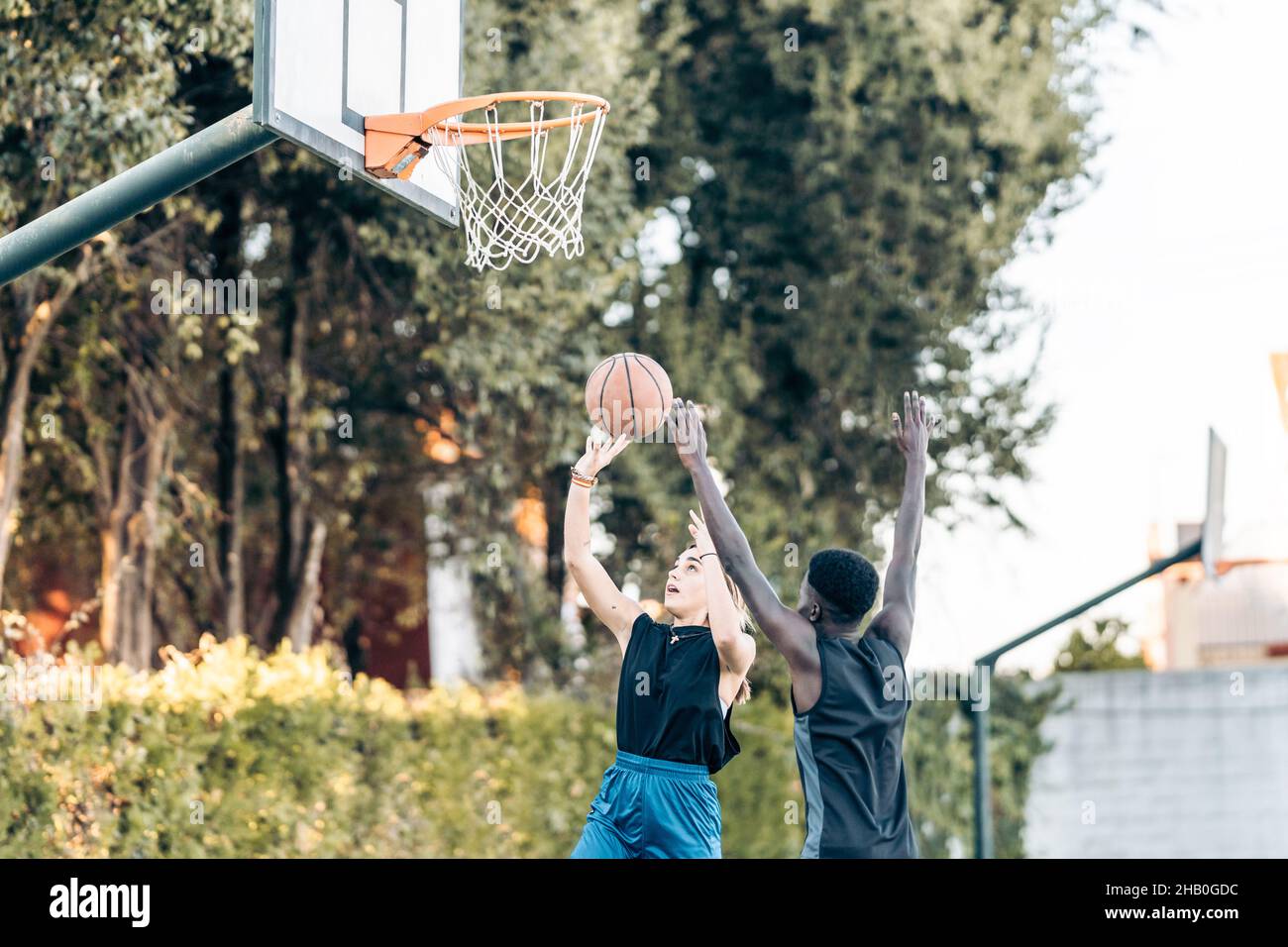 Woman jumping to shoot a ball into a basket during a match between
