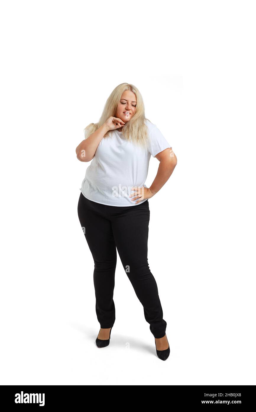 Full-length portrait of plus-size woman wearing white t-shirt and jeans posing isolated on white studio background. Body positive concept Stock Photo