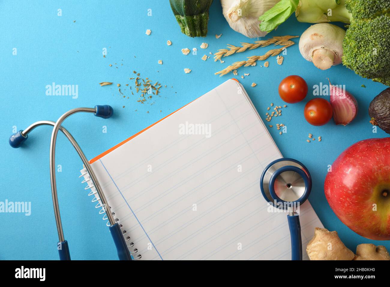 Health care guidelines with natural balanced food with fruits and vegetables and notepad with blank sheet on blue table. Top view. Horizontal composit Stock Photo