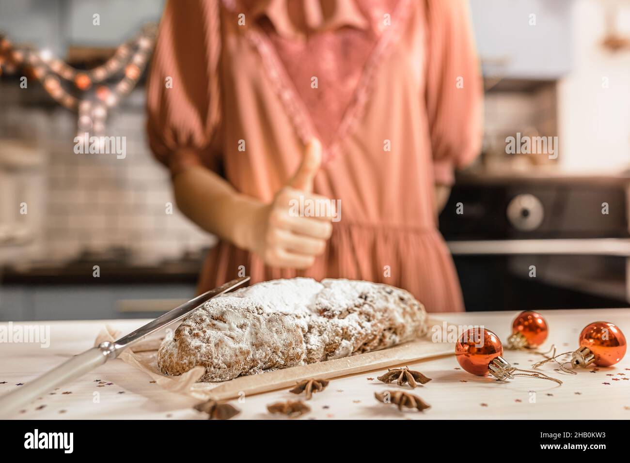 girl in festive outfit cooks traditional German festive Stollen cupcake. Blurred symbol with super hand. Christmas Eve in homely holiday atmosphere Stock Photo