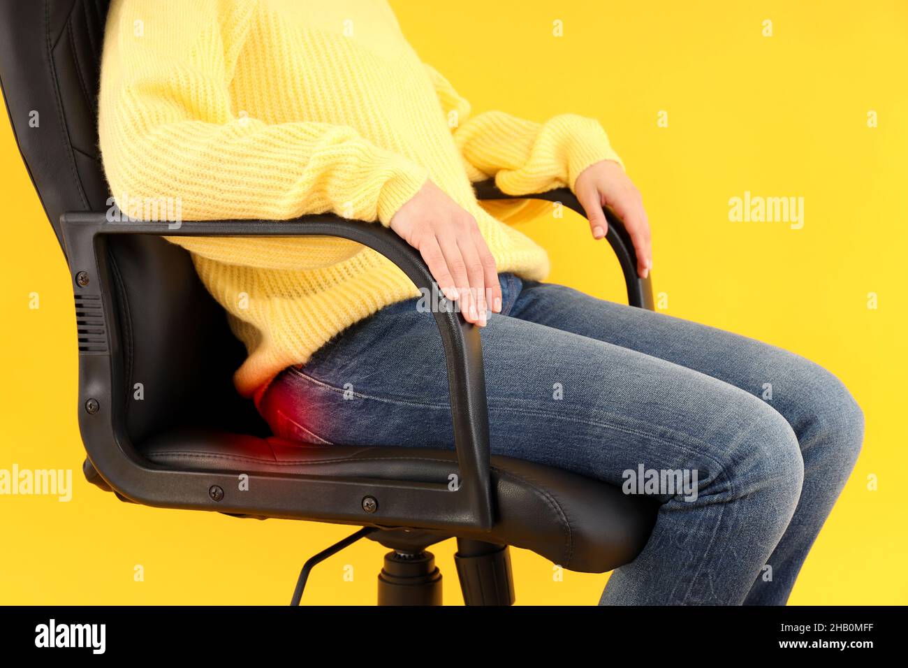 Woman sitting on chair with pain on yellow background. Hemorrhoids