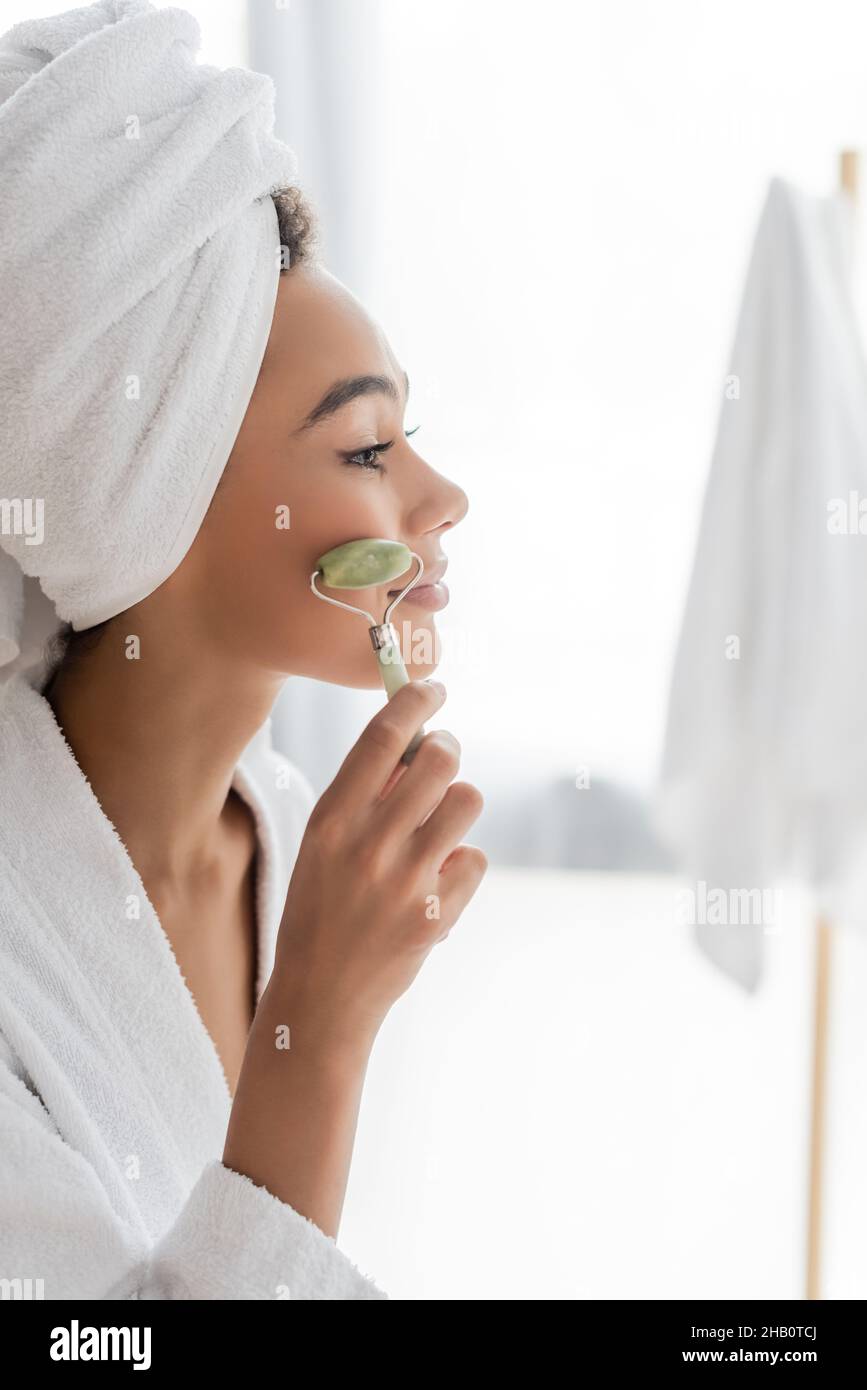 side view of pleased african american woman in bathrobe and towel ...