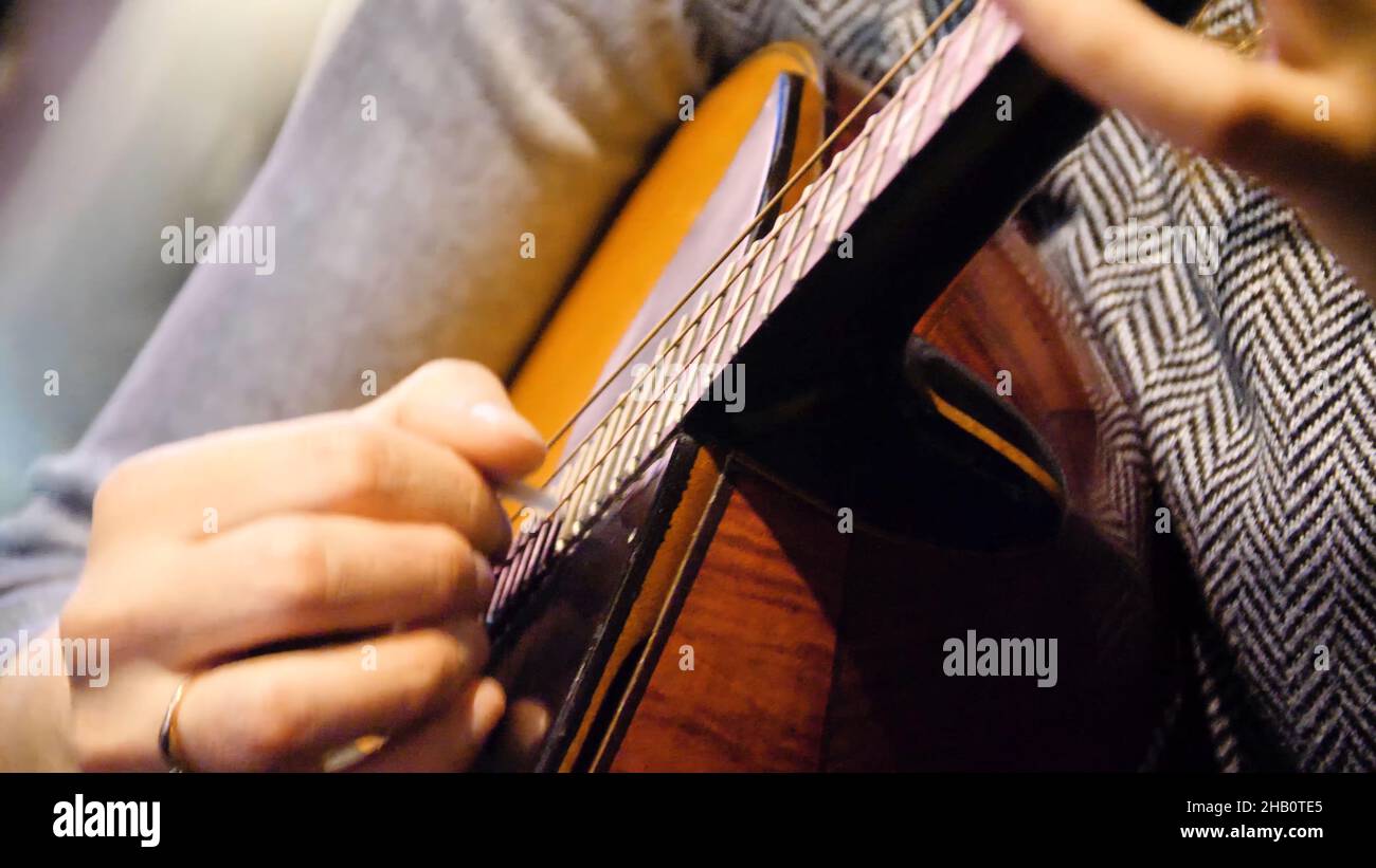 Closeup beautiful acoustic guitar being played by woman sitting down