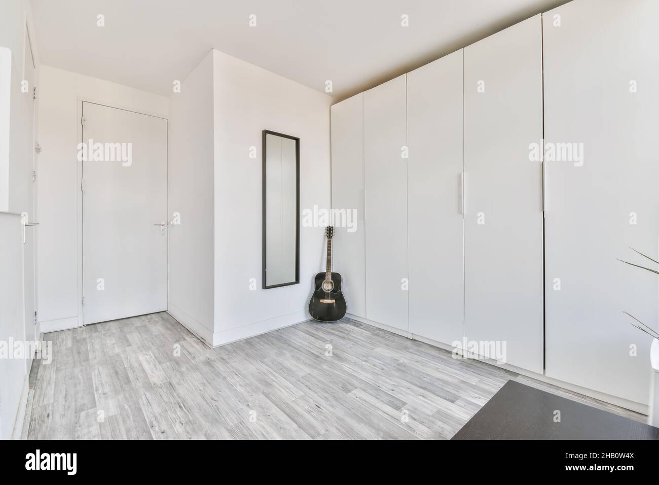 Cozy room with a large white wall cabinet and a guitar Stock Photo
