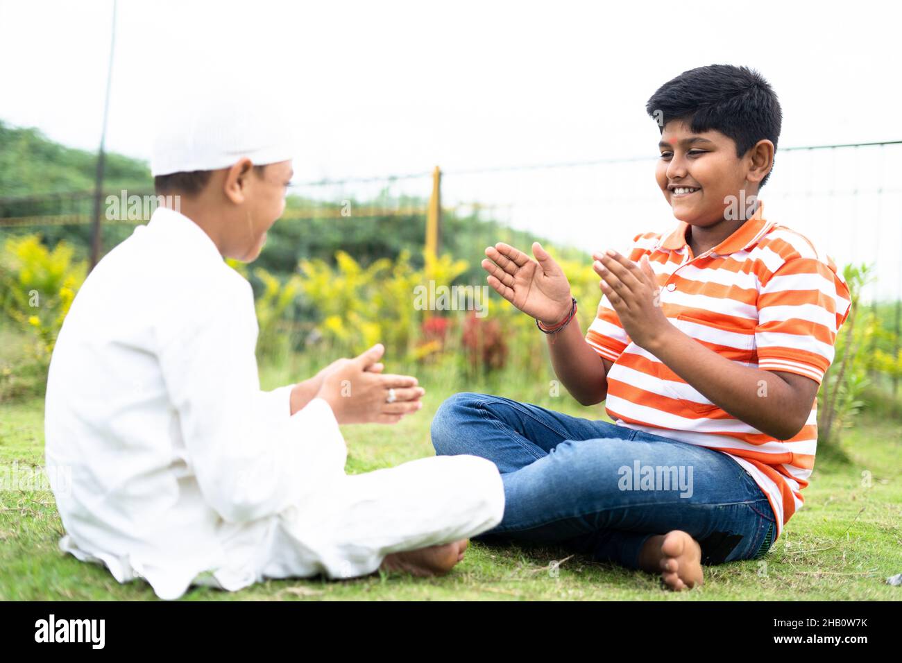 Happy indian multiethnic kids playing slapping and clapping hand game at park - concept of childhood outdoor activities, Friendship and Stock Photo