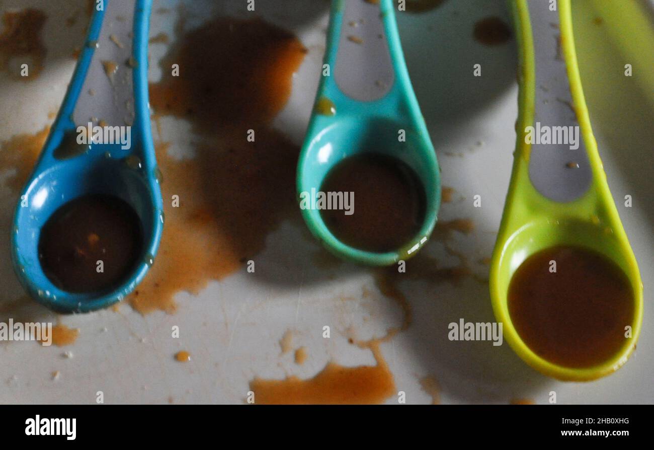 Three spoons of oxtail soup on a toddlers tray - weaning Stock Photo