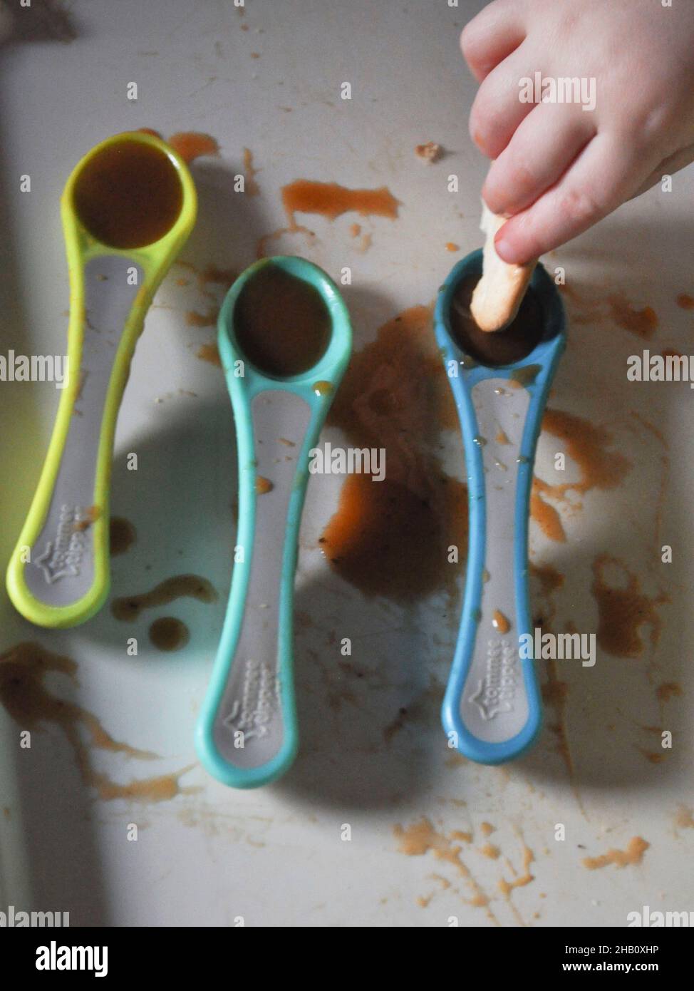 Three spoons of oxtail soup on a toddlers tray - weaning Stock Photo