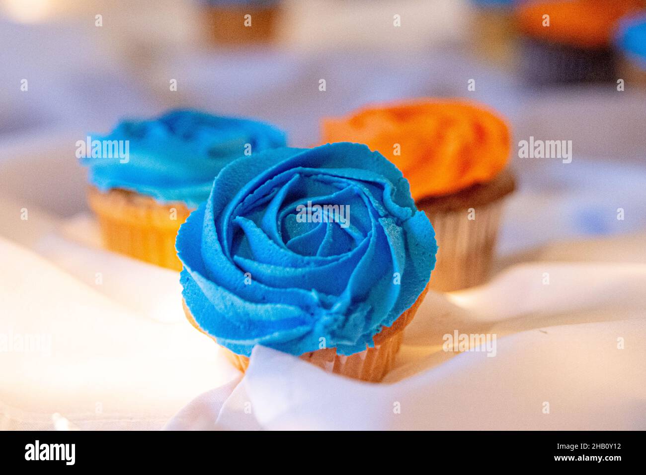 Blue and orange cupcakes on table with bokeh background Stock Photo